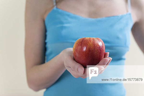 Eine schöne junge Frau  die einen Apfel hält.