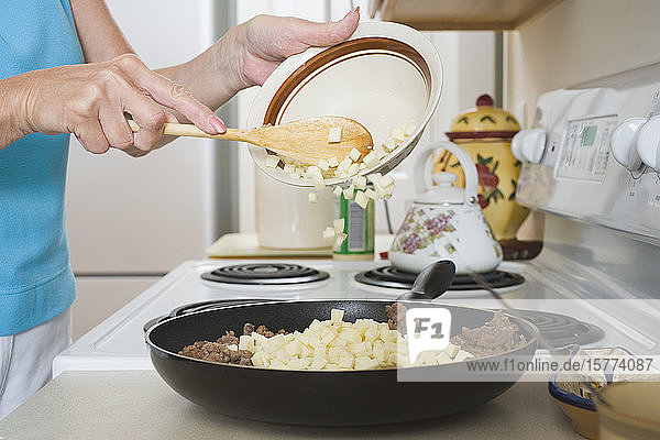Mittelschnittansicht einer Frau beim Kochen in der Küche
