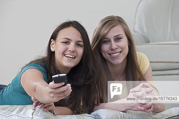 Zwei Mädchen im Teenageralter mit einer auf die Kamera gerichteten Fernbedienung