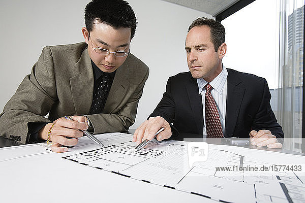 Two architects discussing on blueprints in an office.