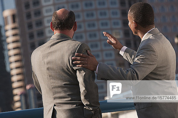 Businessmen sharing insights as they look out towards buildings in an urban area