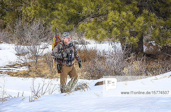 Hunter with snowshoes  rifle and binoculars walking in the snow; Denver  Colorado  United States of America