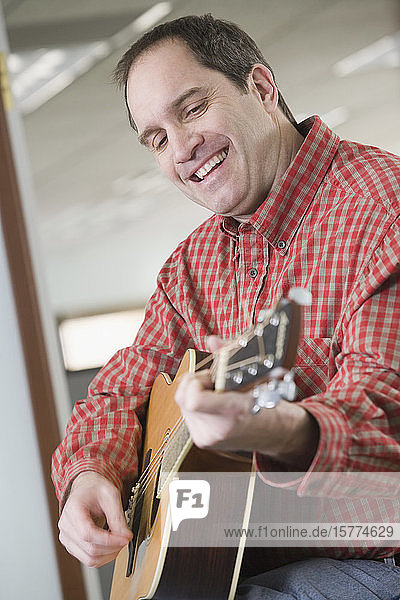 Side profile of a mid adult man playing a guitar