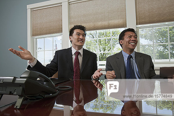 Geschäftsleute sitzen an ihrem Arbeitsplatz in einem Konferenzraum zusammen