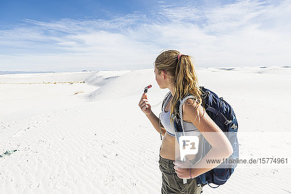A teenage girl hiking across white sand dunes