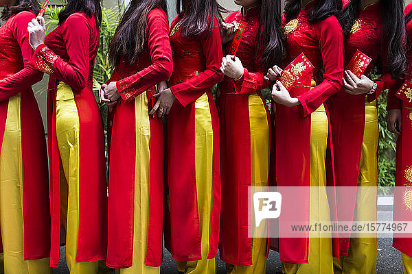 Nahaufnahme einer Reihe von jungen Frauen in traditionellen roten und gelben Kleidern vor einer Hochzeit.