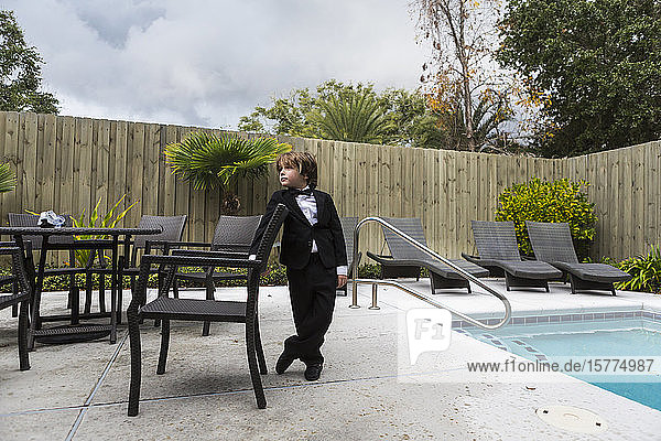 Ein Junge in formellem Gewand steht am Pool
