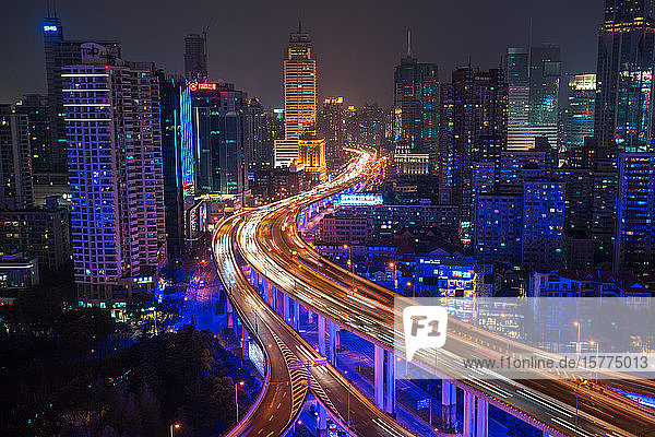 Erhöhte Ansicht eines gestapelten Straßenkreuzes und der Skyline von Shanghai in der Abenddämmerung  Shanghai  China