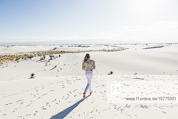 A teenage girl standing looking at a vast open space of sand dunes.