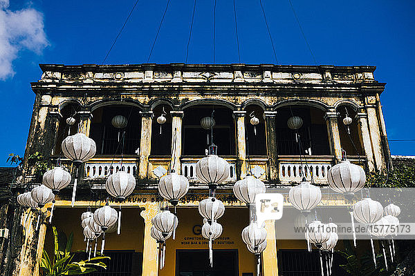 Traditionelle weiße Laternen  die vor einem historischen Gebäude hängen.