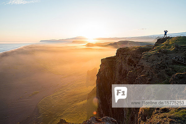 Mann beim Blick auf den Sonnenuntergang von der Dyrholaey-Halbinsel in der Nähe von Vik  Südisland (Sudurland)  Island  Polarregionen