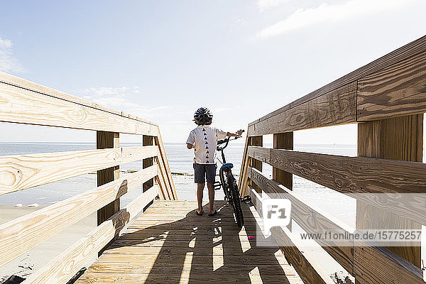 Ein kleiner Junge auf einer Holzbrücke mit seinem Fahrrad