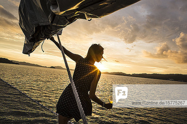 Frau mit Weinglas in der Hand an Bord eines Schiffes  Dinner-Kreuzfahrt bei Sonnenuntergang auf dem Indischen Ozean.
