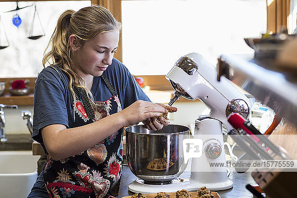 Ein Mädchen im Teenager-Alter benutzt den Mixer in der Küche.