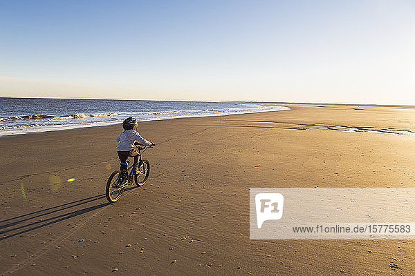 Ein kleiner Junge fährt Fahrrad am Strand