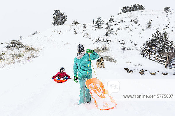 A boy and girl sledding down hill in snow