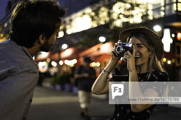 Young woman taking picture of young man on street