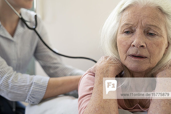 Hauspflegerin untersucht den Rücken einer älteren Frau