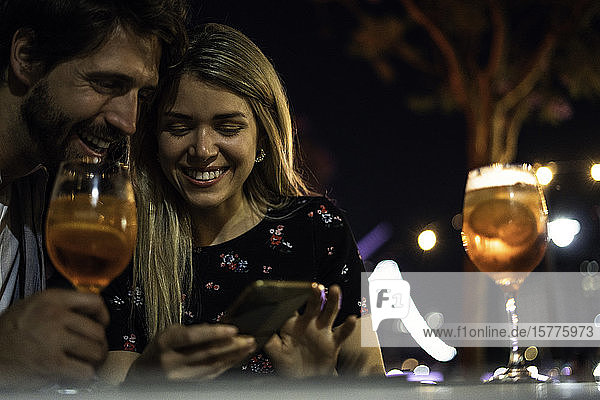 Junges Paar benutzt Smartphone in einem Straßencafé