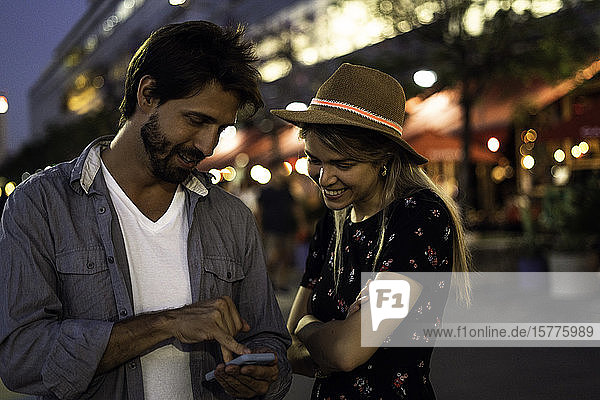 Young couple using smartphone on street