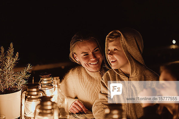 Lächelnde Mutter schaut Kinder an während sie im Restaurant am Tisch sitzt