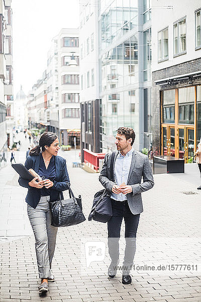 Männliche und weibliche Geschäftsleute unterhalten sich beim Spaziergang in der Stadt