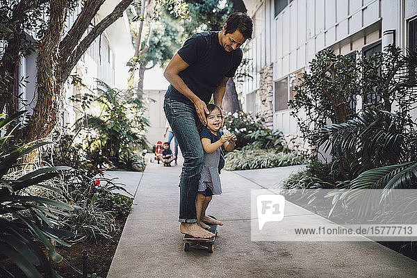 Glücklicher Vater und Tochter beim Skateboarden auf dem Fussweg