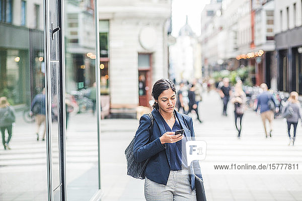 Geschäftsfrau benutzt Telefon  während sie in der Stadt steht