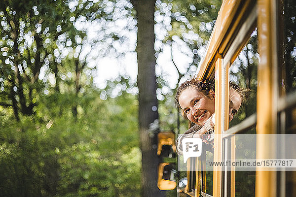 Lächelnde Frau schaut durch Wohnwagenfenster beim Camping im Wald