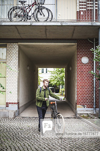 Male architect with bicycle walking on footpath