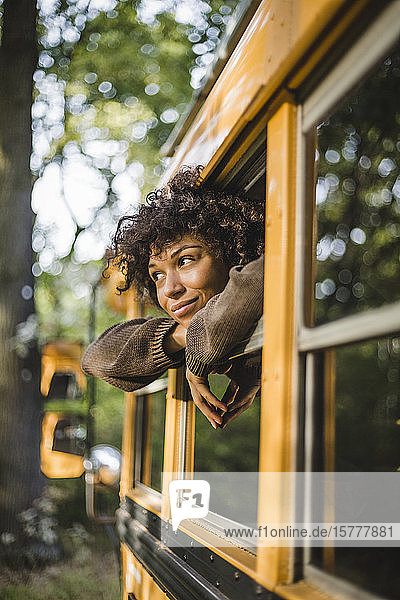 Nachdenkliche junge Frau schaut durch Wohnwagenfenster beim Camping im Wald