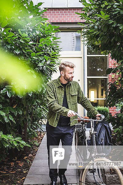 Männlicher Architekt mit Fahrrad gegen Haus gelaufen