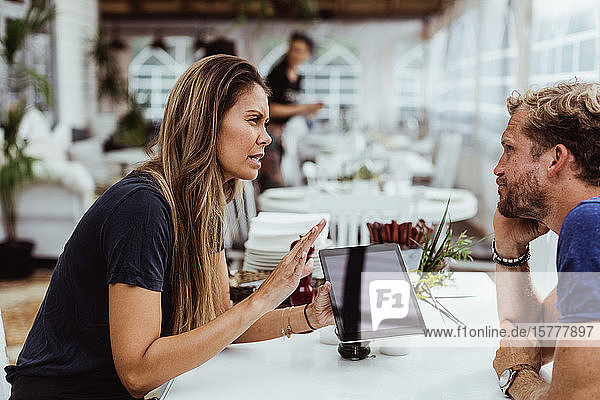 Female owner taking order from customer while using digital tablet in restaurant