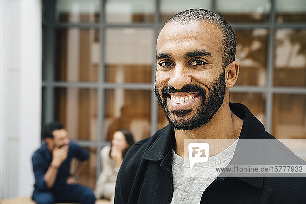Porträt eines glücklichen männlichen Unternehmers vor dem Büro stehend