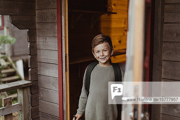 Porträt eines lächelnden Jungen  der während des Urlaubs vor der Haustür steht