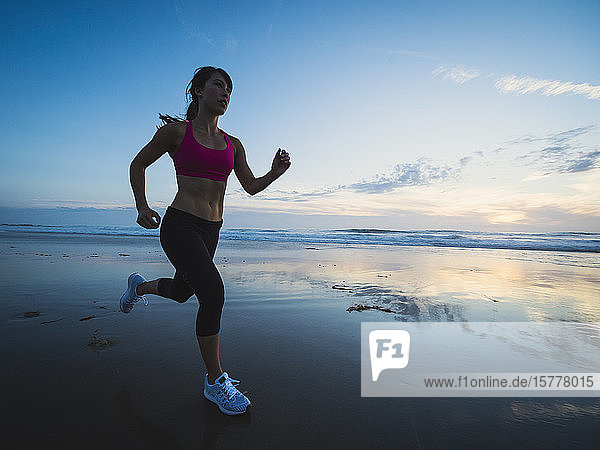 Frau in Sportkleidung läuft am Strand