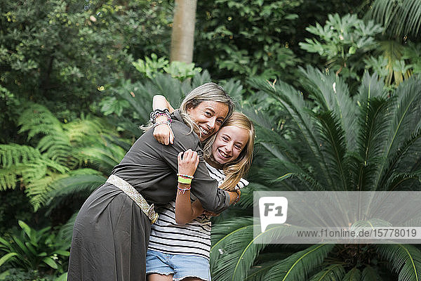 Mutter und Tochter lächelnd und sich umarmend am Busch