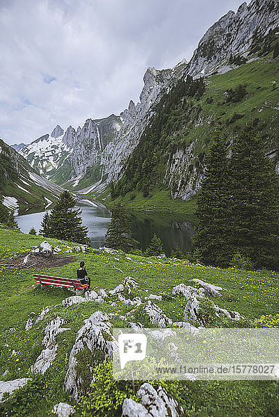Woman sitting on bench by mountains in Appenzell  Switzerland