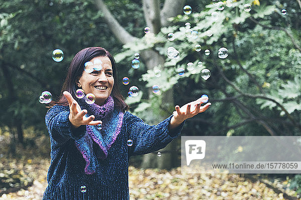 Lächelnde Frau spielt mit Seifenblasen