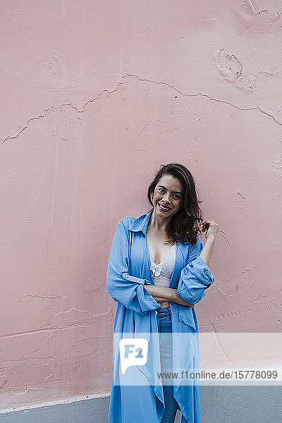 Lächelnde Frau in Blau vor rosa Wand