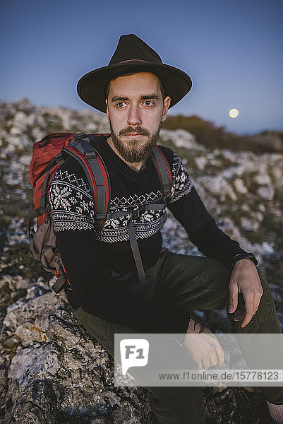 Man sitting on rock at sunset