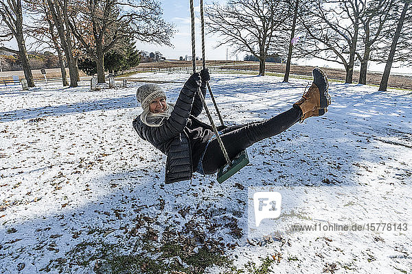 Smiling woman on swing in snow