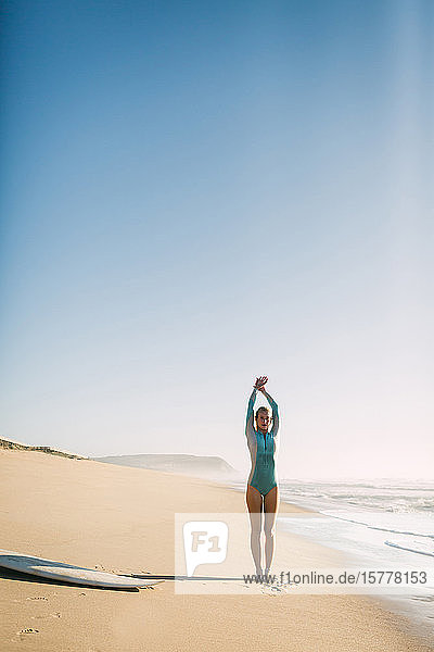 Frau im Neoprenanzug beim Stretching am Strand