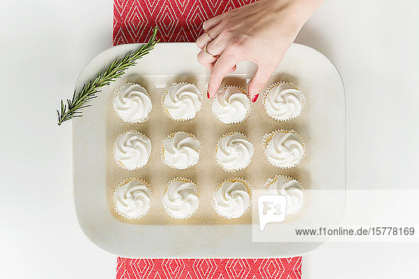 Woman's hand reaching for cupcake on tray
