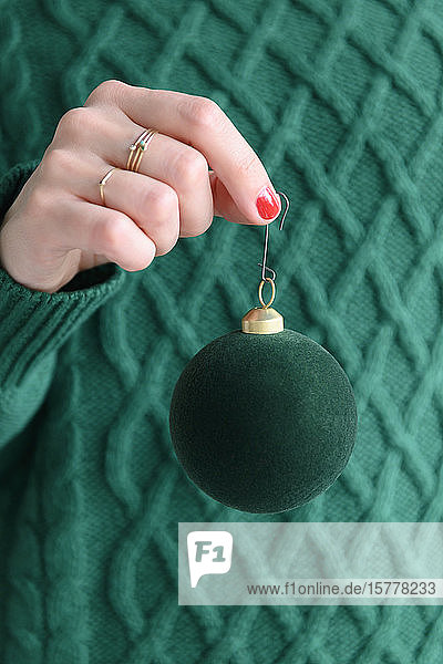 Woman wearing green holding green bauble