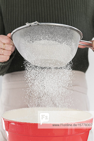 Woman sifting flour into bowl