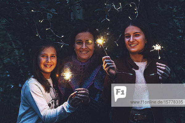 Mother and daughters smiling and holding sparklers