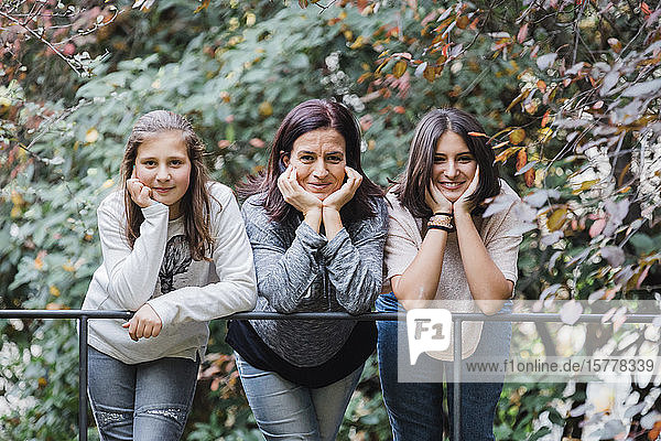 Mother and daughters smiling and leaning on railing