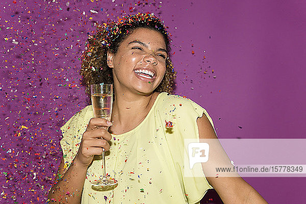 Smiling woman holding champagne glass under confetti