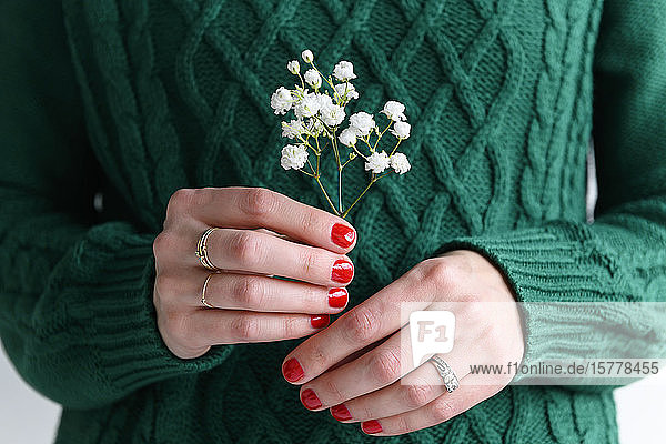 Woman wearing green holding white flowers